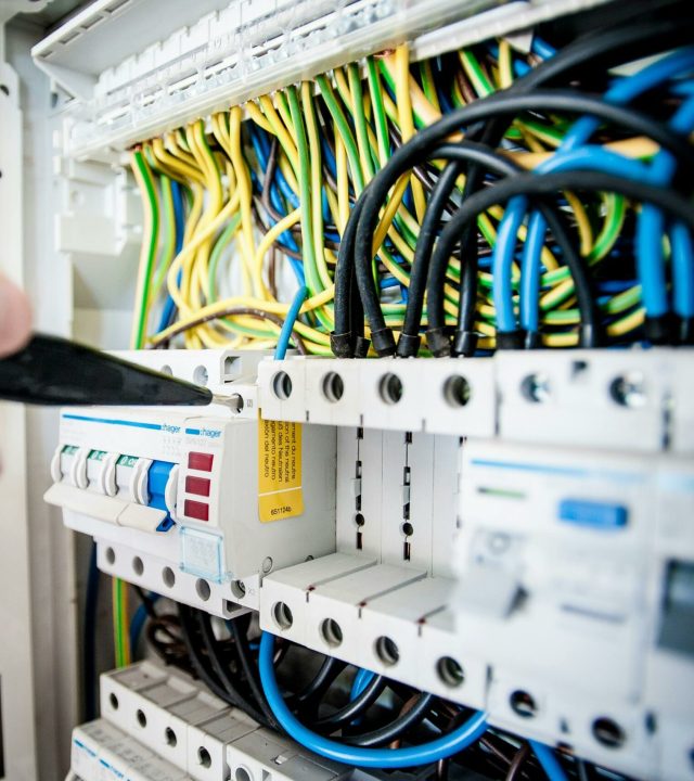 pexels-photo-257736-257736 Hand of electrician working on a circuit breaker panel with colorful wires, ensuring safe electrical connections.